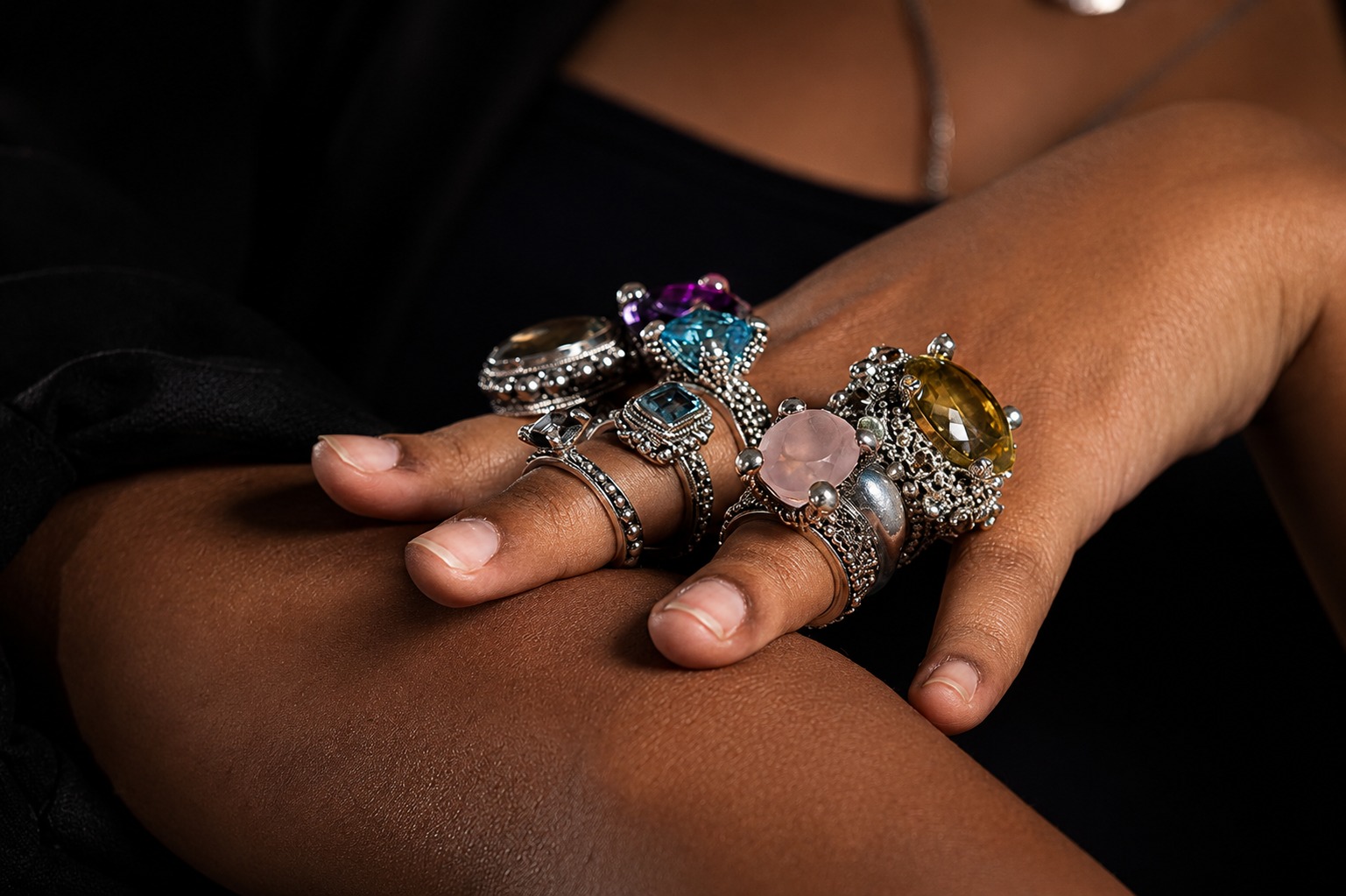 Hand wearing ornate silver rings with colourful gemstones